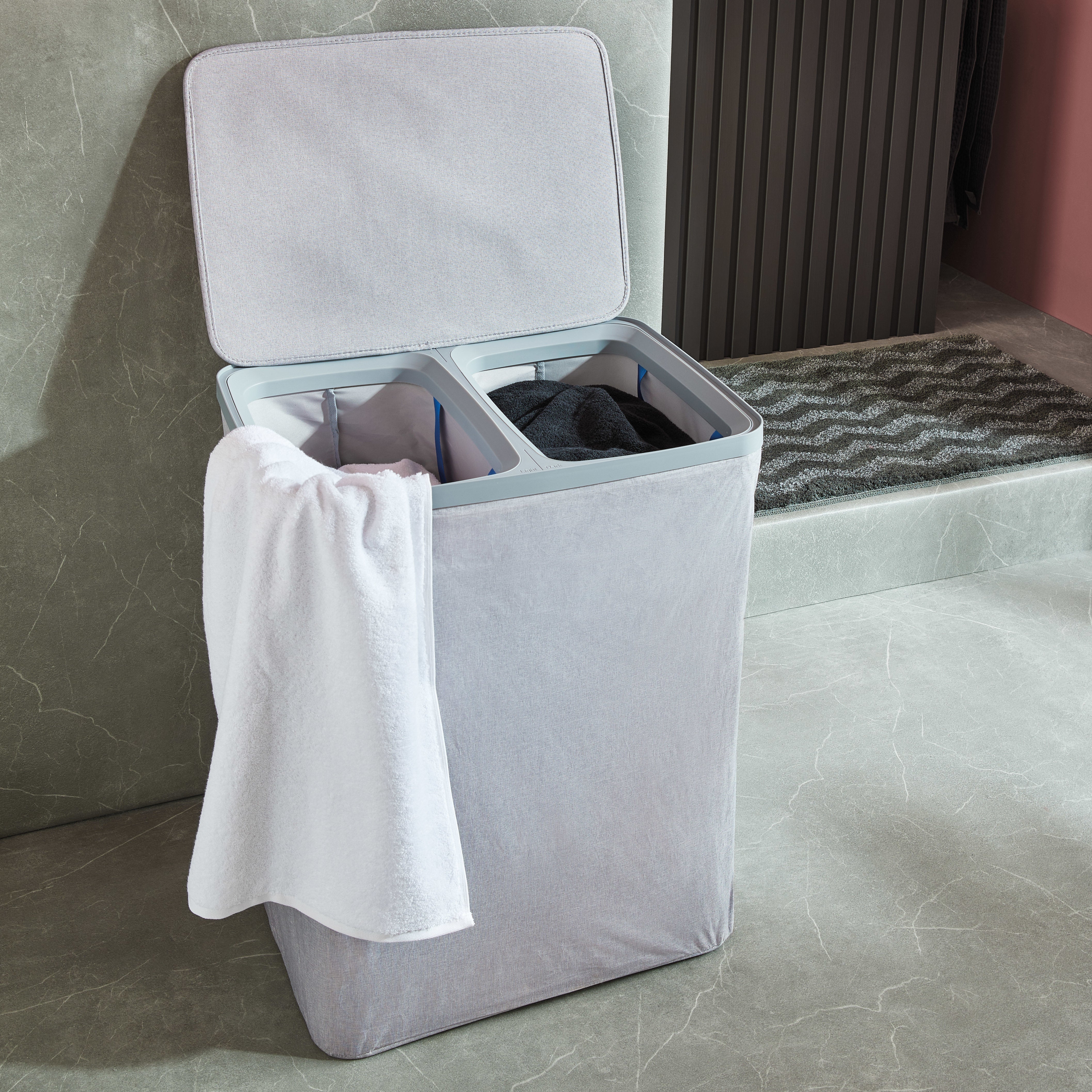 Grauer Kleine Wolke Wäschesammler mit zwei Fächern und weißem Handtuch in modernem Bad.