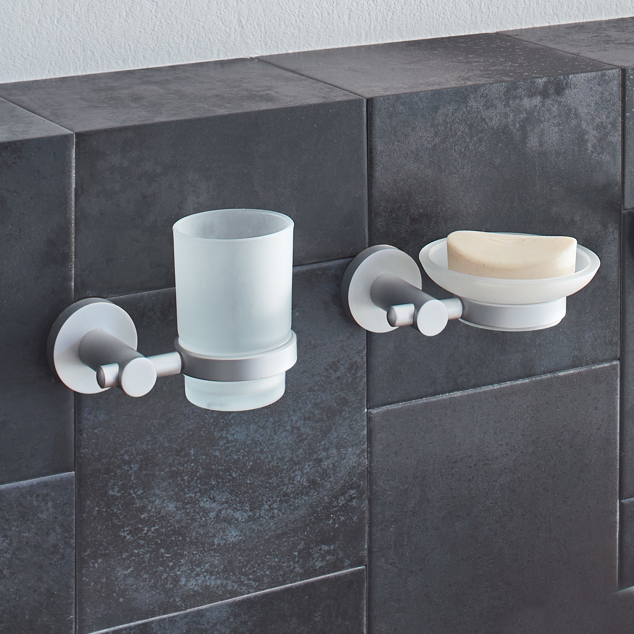 Kleine Wolke Wandaccessoires mit Becher und Seifenschale sind auf dunklen Badfliesen ohne Bohren montiert.