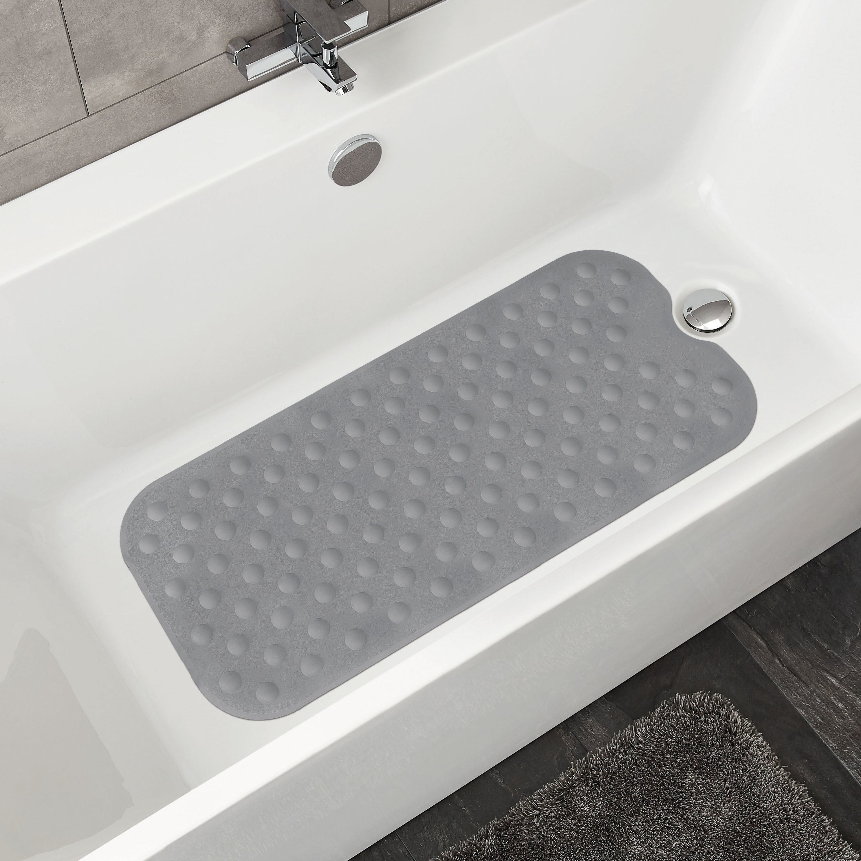 Graue Wanneneinlage mit Noppen liegt in einer weißen Badewanne im modernen Badezimmer.