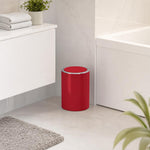 Roter Bad-Abfalleimer mit silbernem Rand steht neben der Badewanne.
