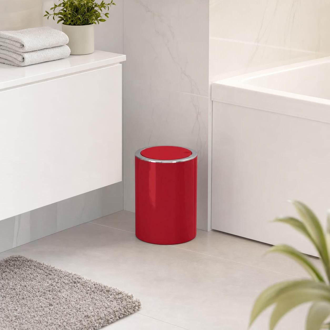 Roter Bad-Abfalleimer mit silbernem Rand steht neben der Badewanne.