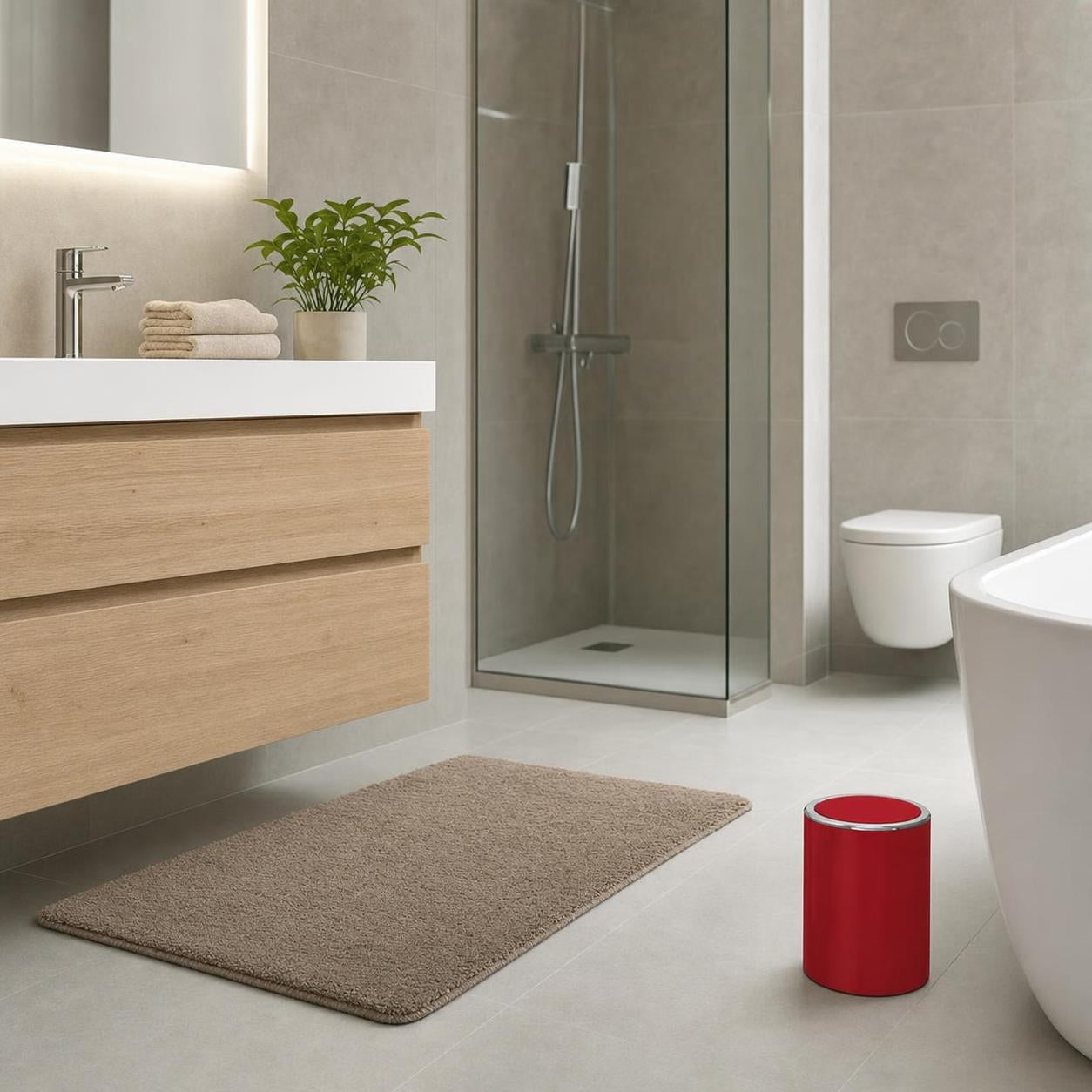Ein roter Badabfalleimer steht neben der Badewanne im modernen Bad.