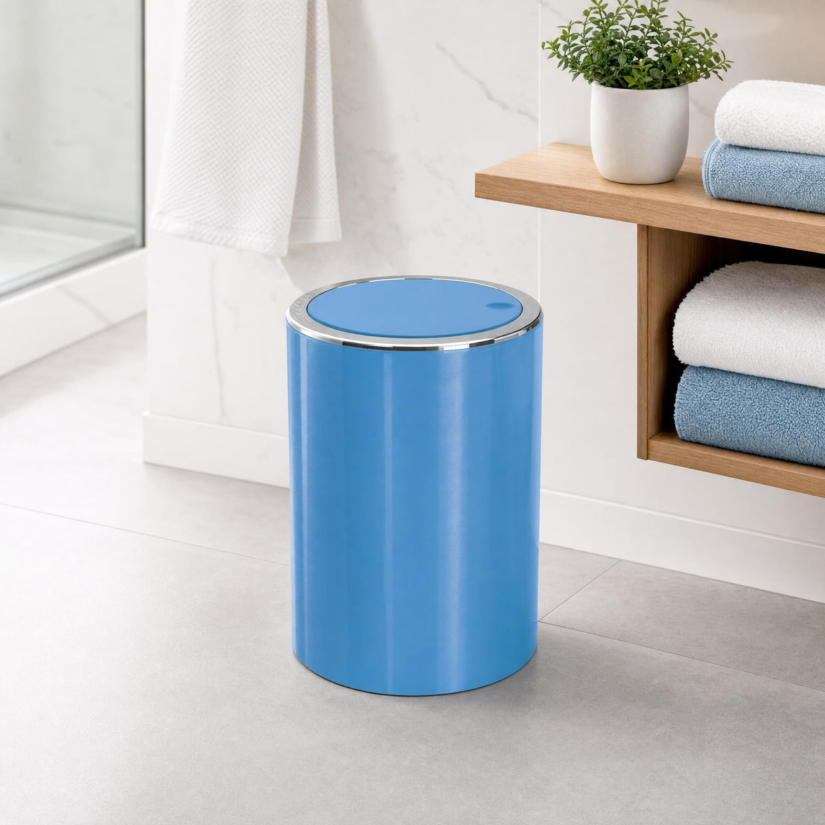 Blauer Mülleimer im modernen Bad neben Holzregal mit Handtüchern.