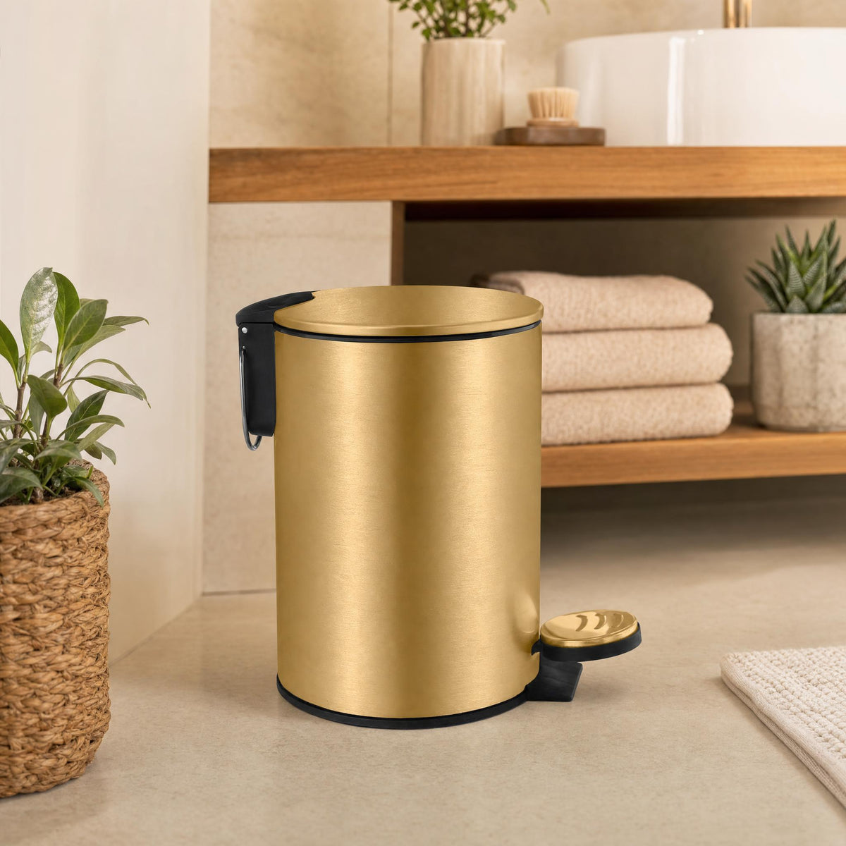 Goldfarbener Treteimer im Badezimmer vor Holzregal mit Handtüchern.