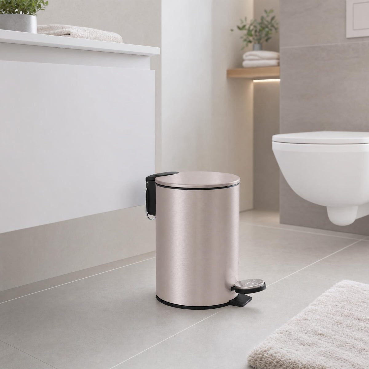 Silberfarbener Treteimer in modernem Bad neben Waschtisch und Wand-WC.