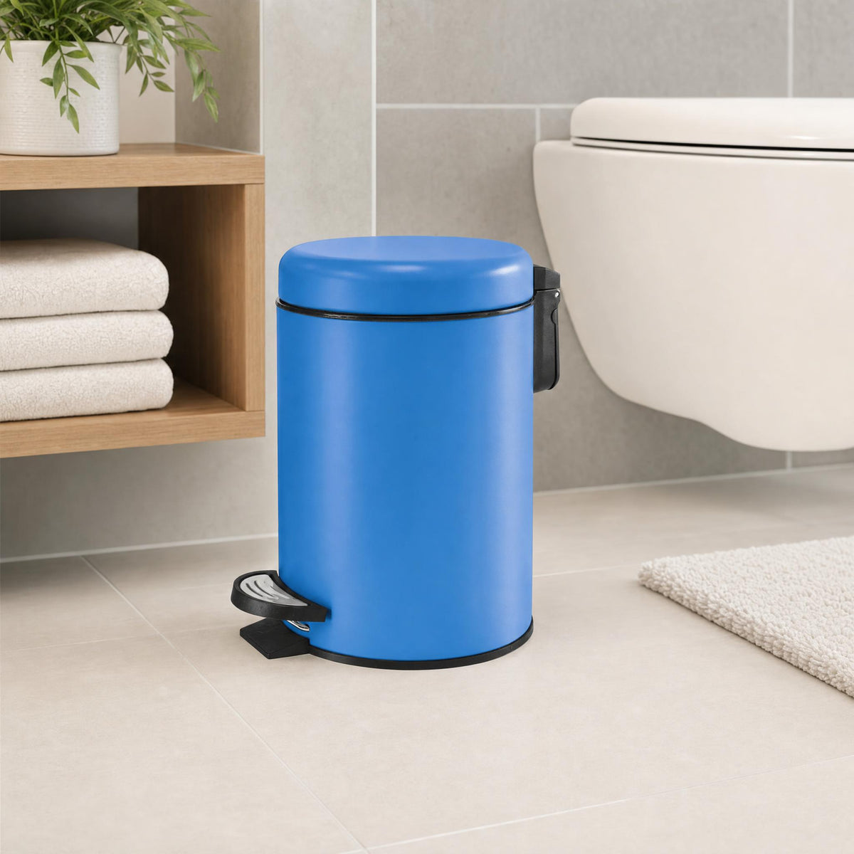 Blauer Treteimer im modernen Bad neben WC, Handtüchern und Holzregal.