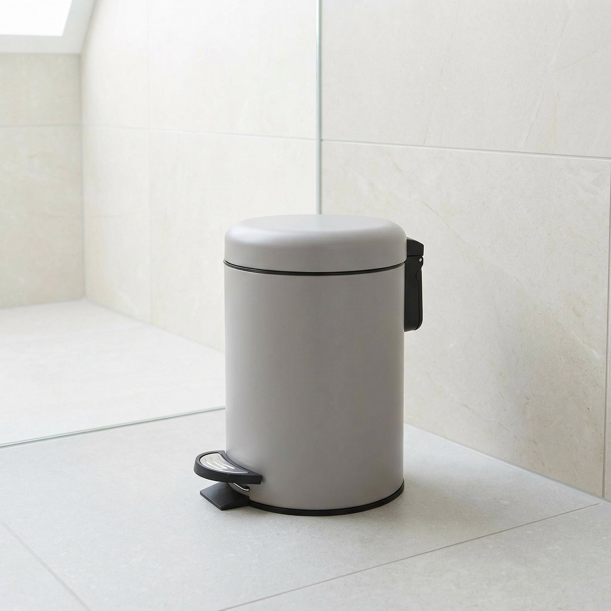 Runder, hellgrauer Treteimer aus Metall in modernem Badezimmer mit Pedal