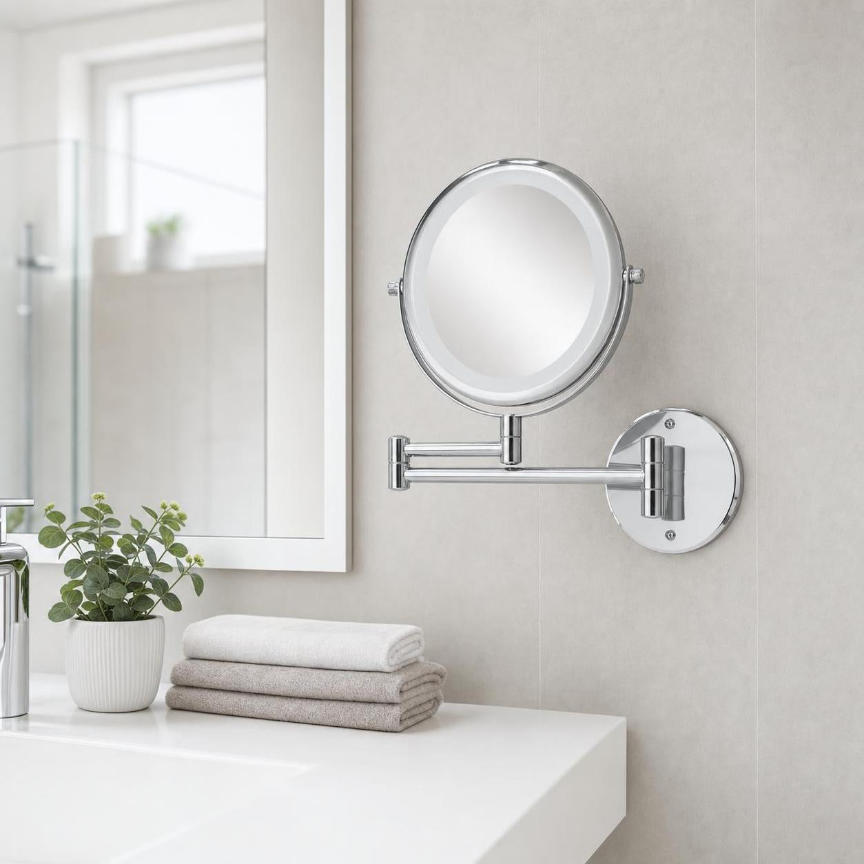 Ein verchromter Wand-Kosmetikspiegel hängt im hellen Badezimmer.