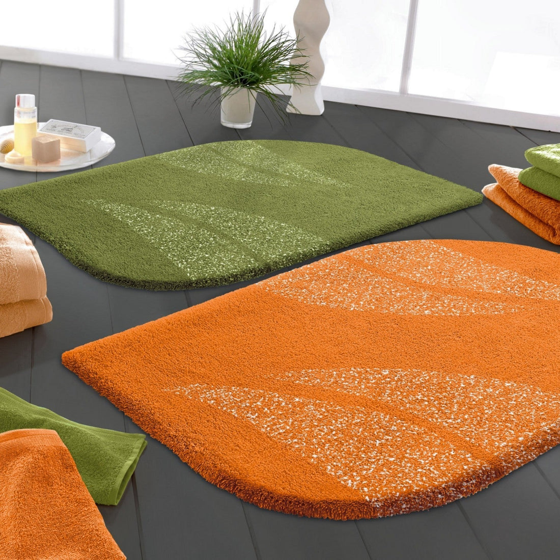 Zwei Badteppiche in orange und grün in Blattform.