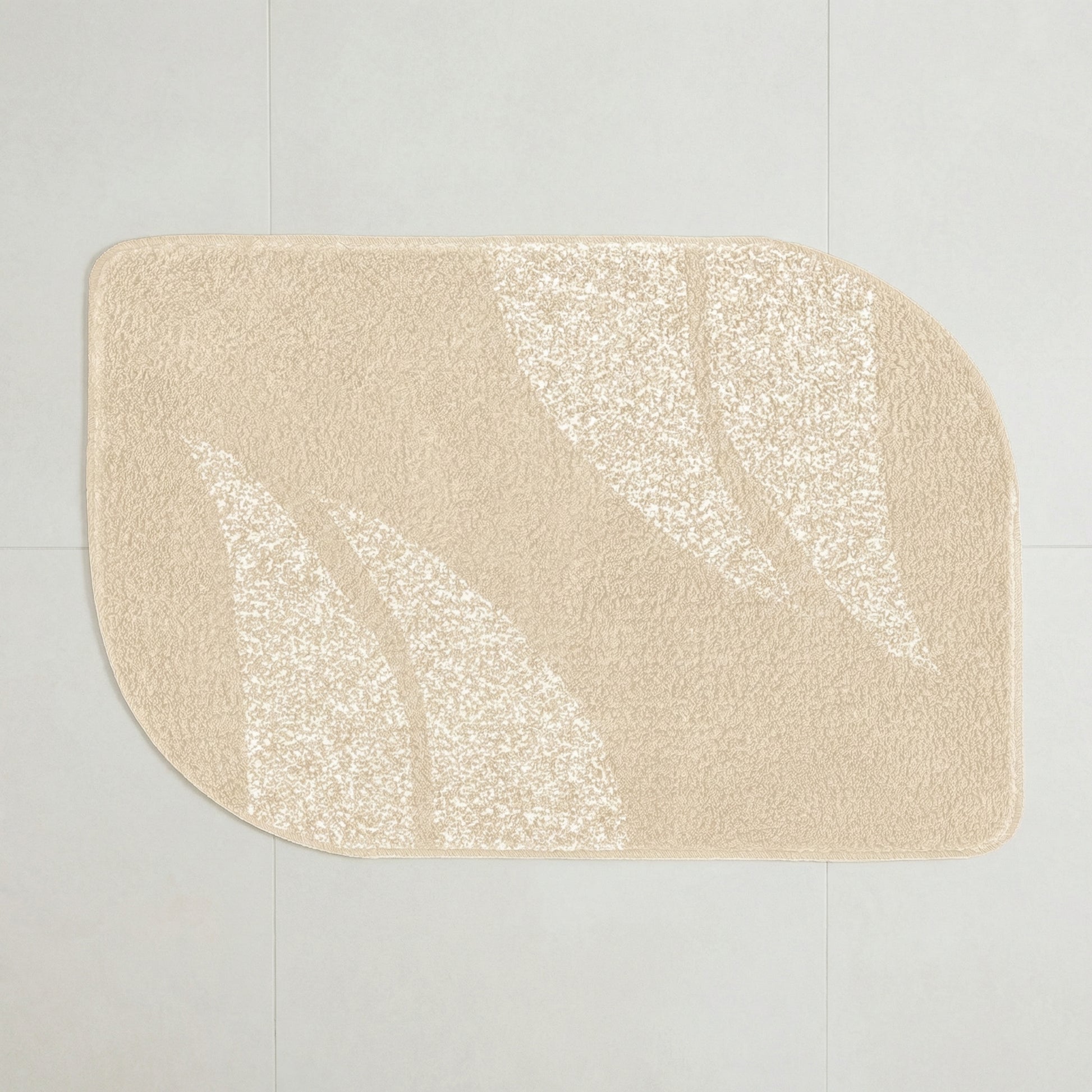 Beige Badematte mit abstraktem Blattmuster auf hellem Fliesenboden