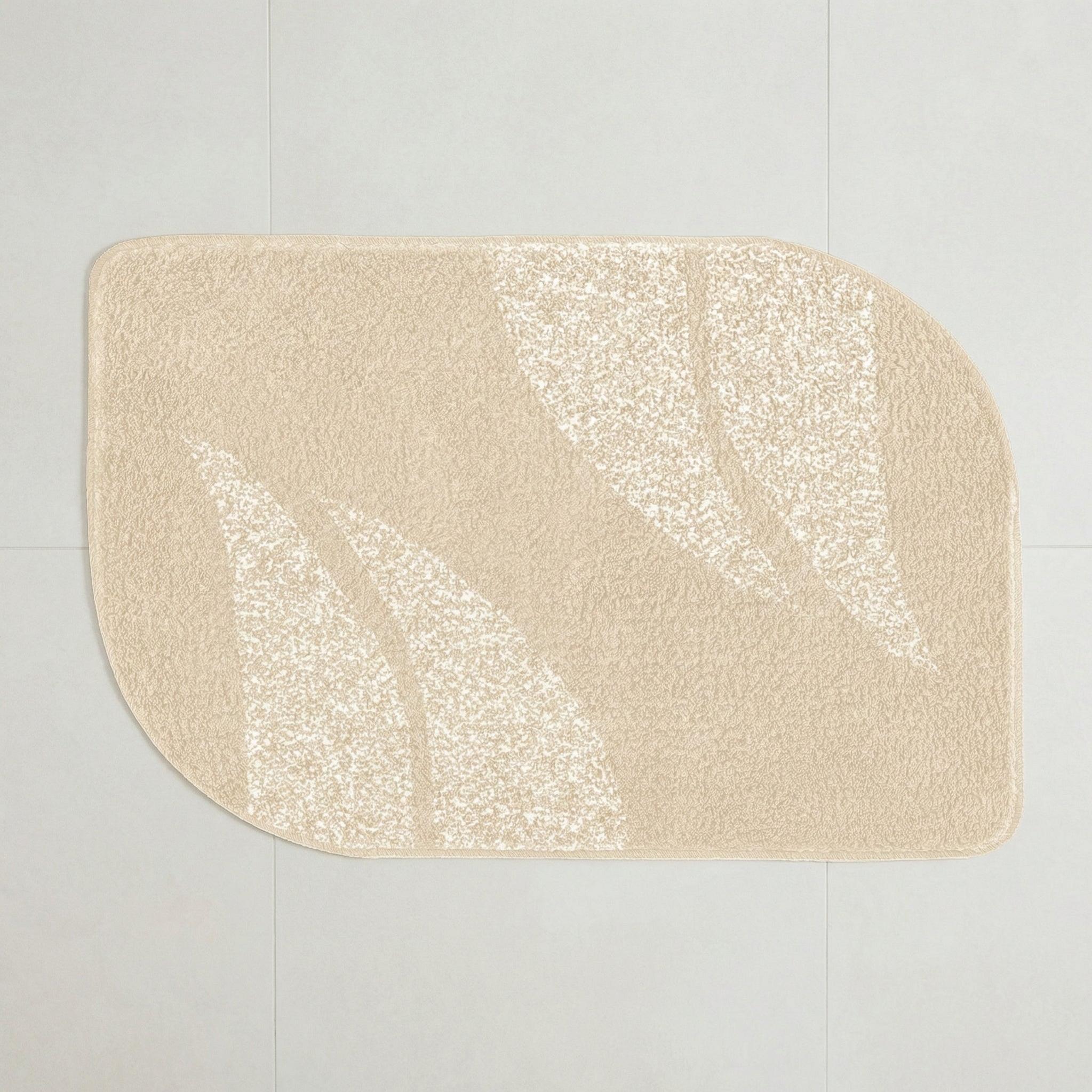 Beige Badematte mit abstraktem Blattmuster auf hellem Fliesenboden