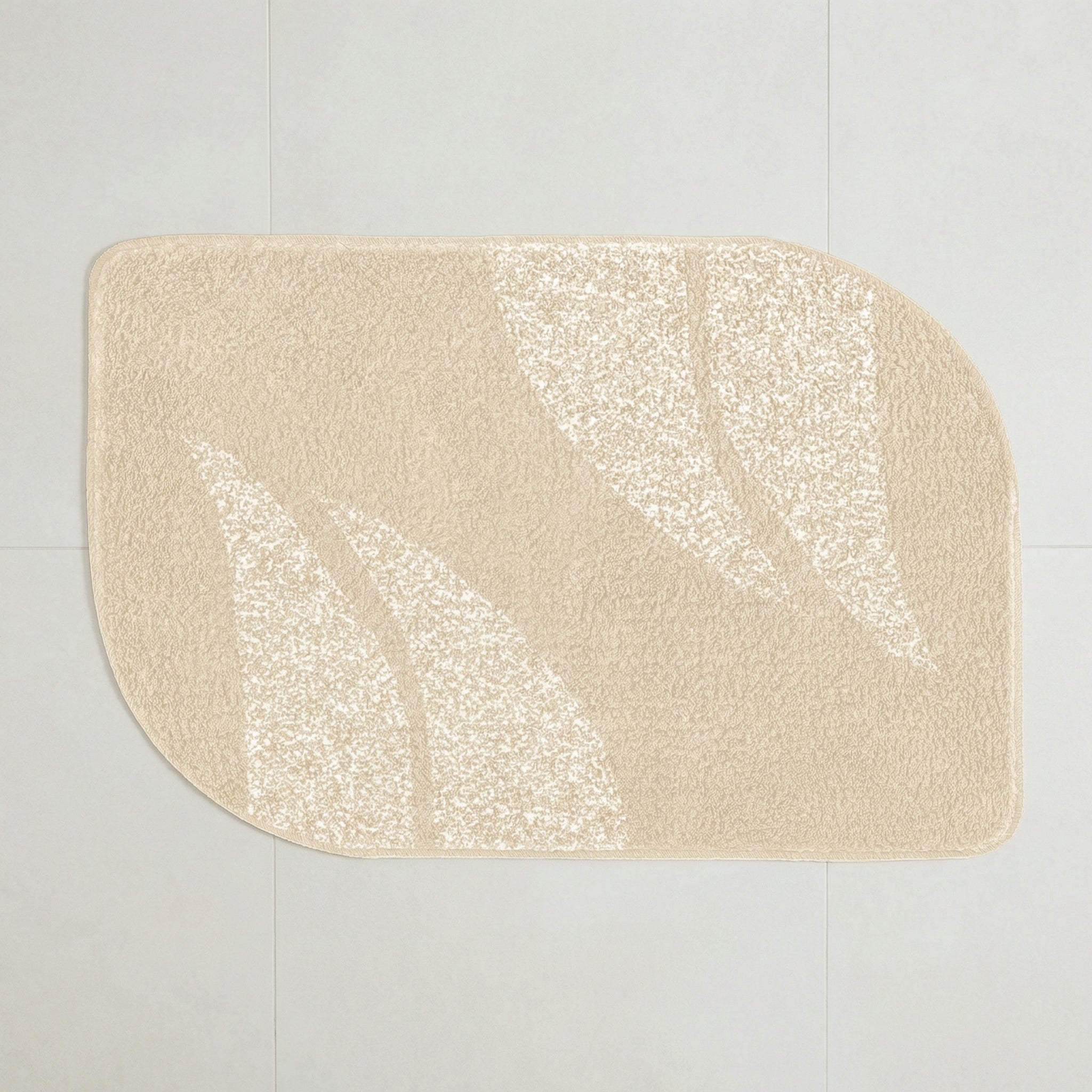 Beige Badematte mit abstraktem Blattmuster auf hellem Fliesenboden