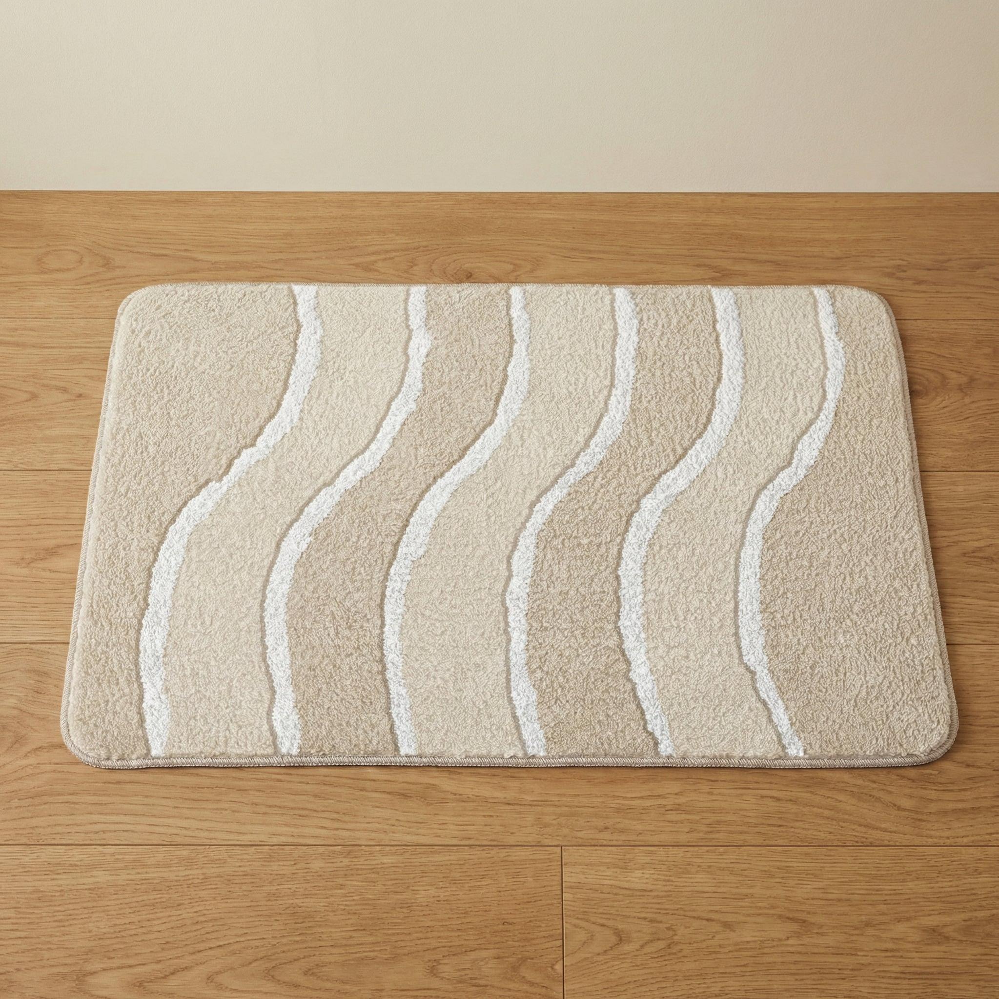Beige Badematte mit weißen geschwungenen Linien auf Holzfußboden liegend