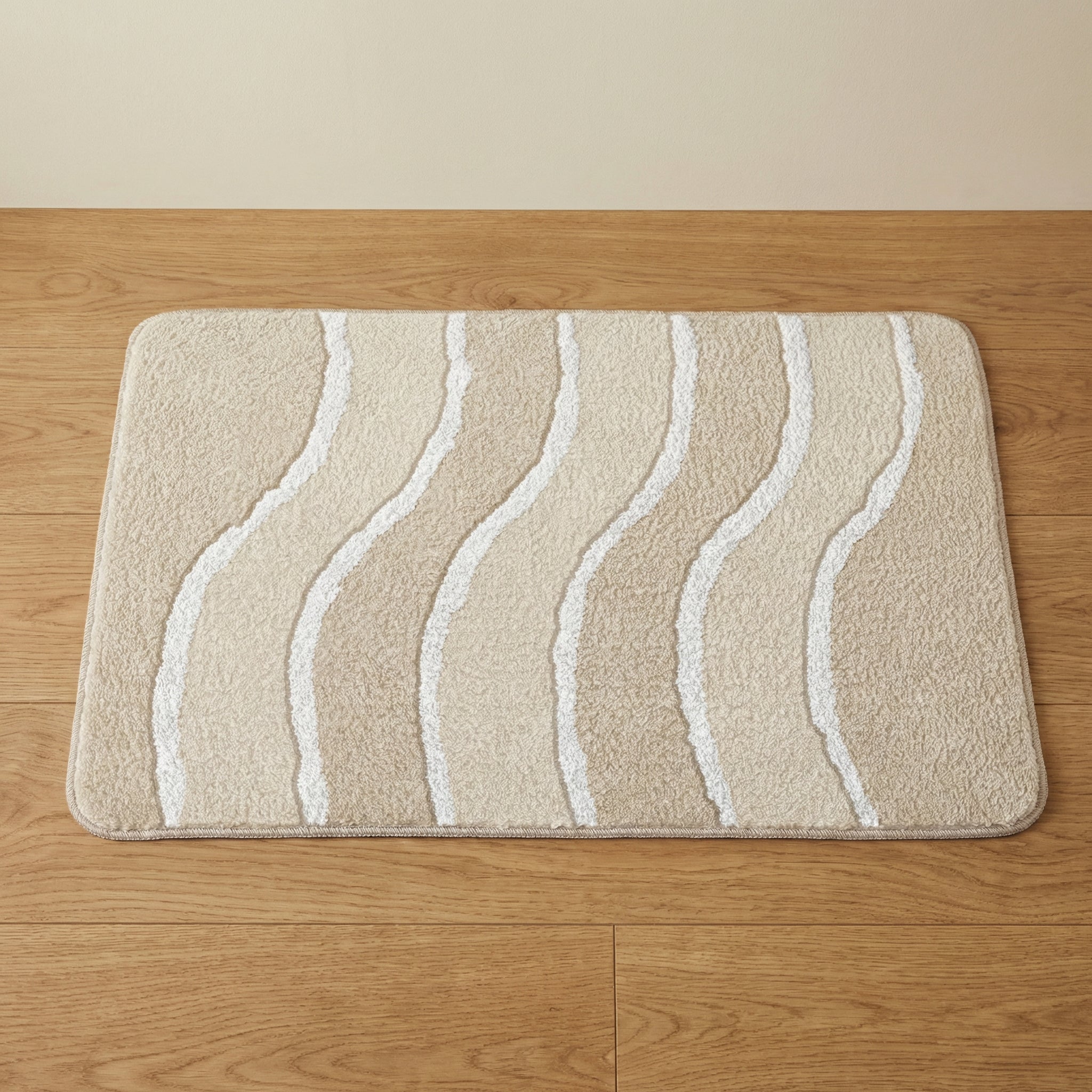 Beige Badematte mit weißen geschwungenen Linien auf Holzfußboden liegend