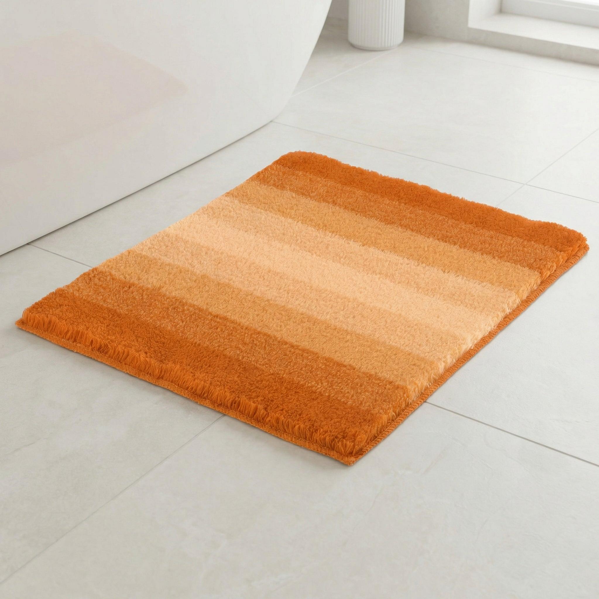Rechteckige Badematte in Orange mit Streifen auf hellen Fliesenboden