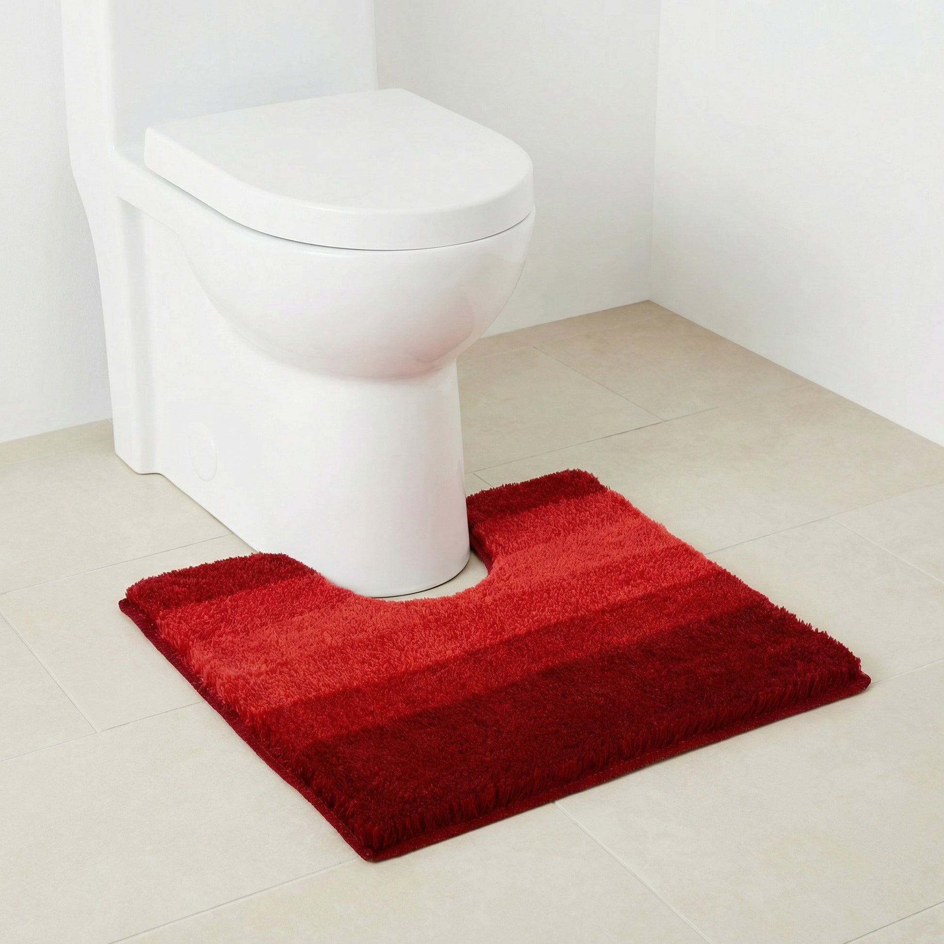 Weiße Toilette mit rot gestreifter Badematte auf hellen Bodenfliesen
