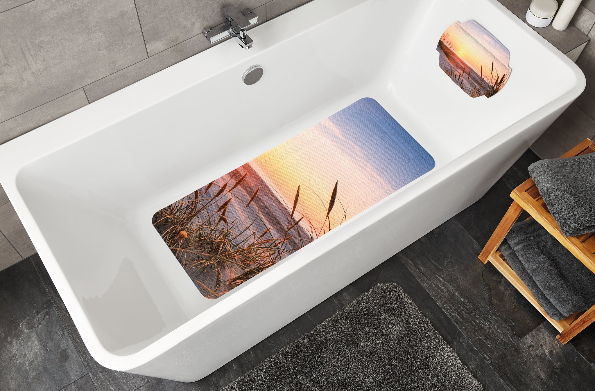 Weiße Badewanne mit Badematte im Strandmotiv und Handtüchern daneben