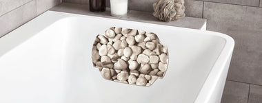 Weiße Badewanne mit rutschfester Badematte im Kieselstein-Design