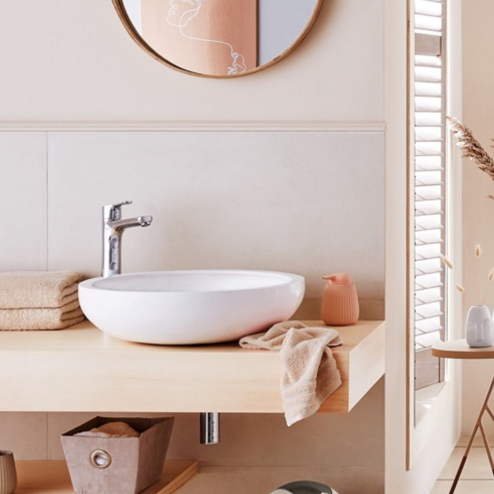 Modernes Bad mit rundem Waschbecken, Handtüchern und Face Me Seifenspender von Kleine Wolke auf Holzkonsole.