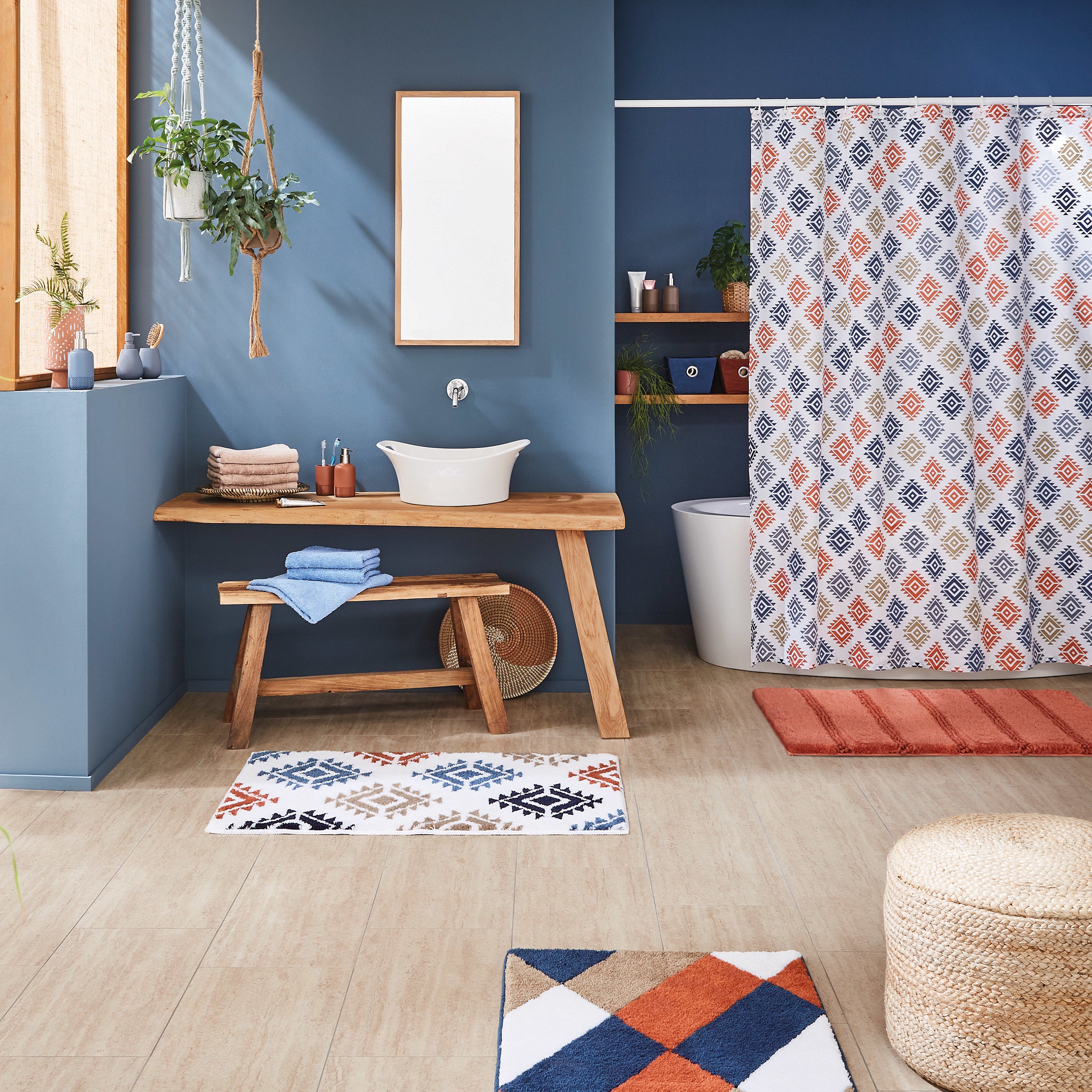 Modernes Bad mit blauem Wänden, Holzwaschtisch, gemustertem Duschvorhang und passenden Badematten.