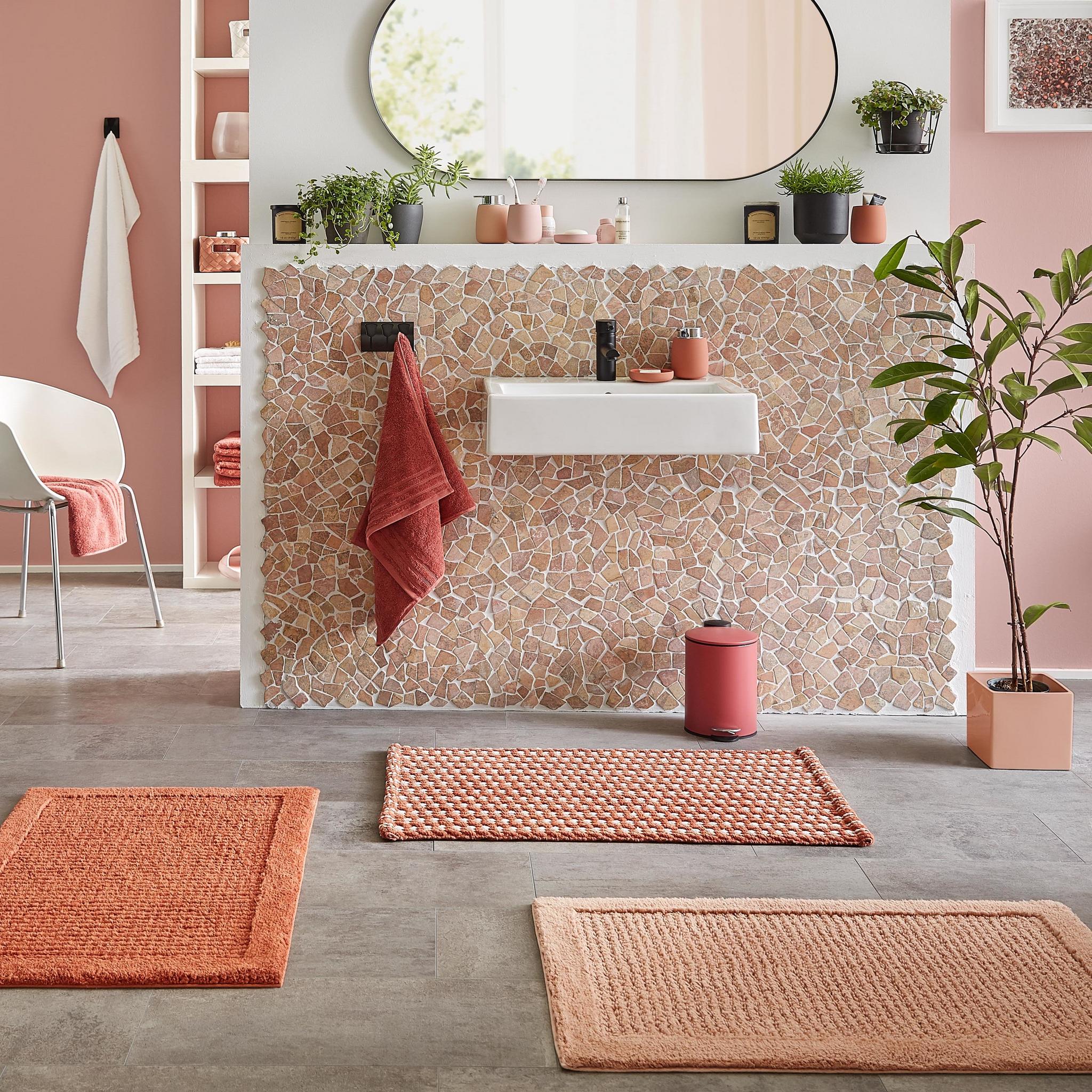 Modernes Bad mit Waschbecken, rosafarbenen Matten und Accessoires