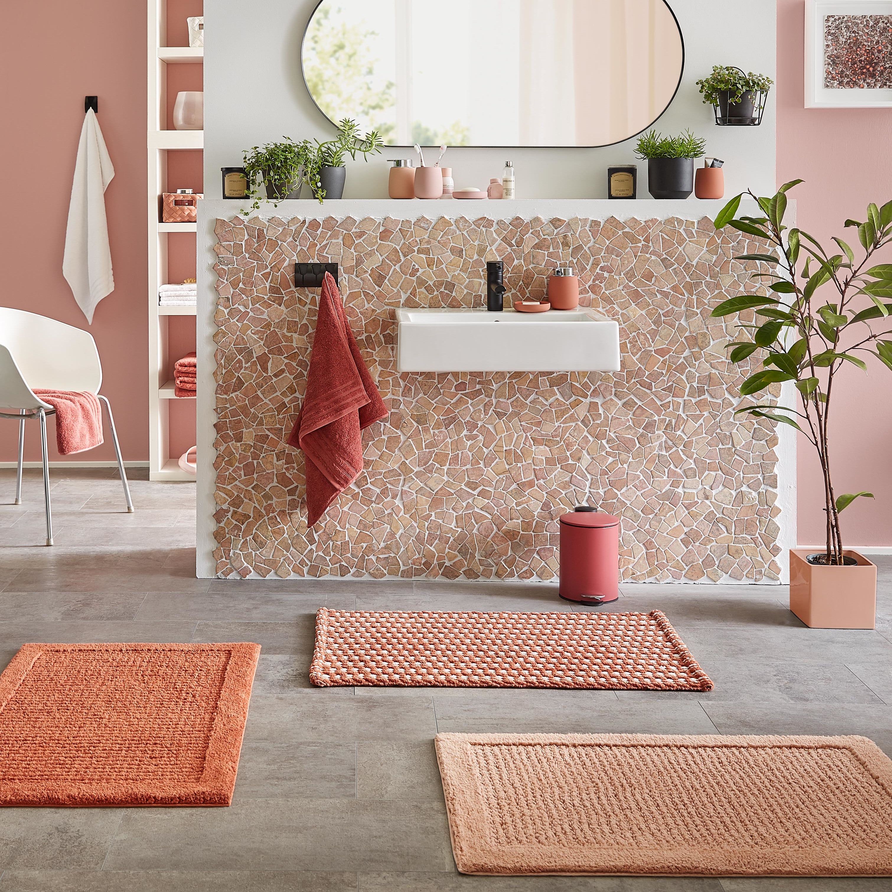 Moderne Badszene mit orangen Kleine Wolke Badematten vor Waschtisch mit Mosaikfliesen und Deko.