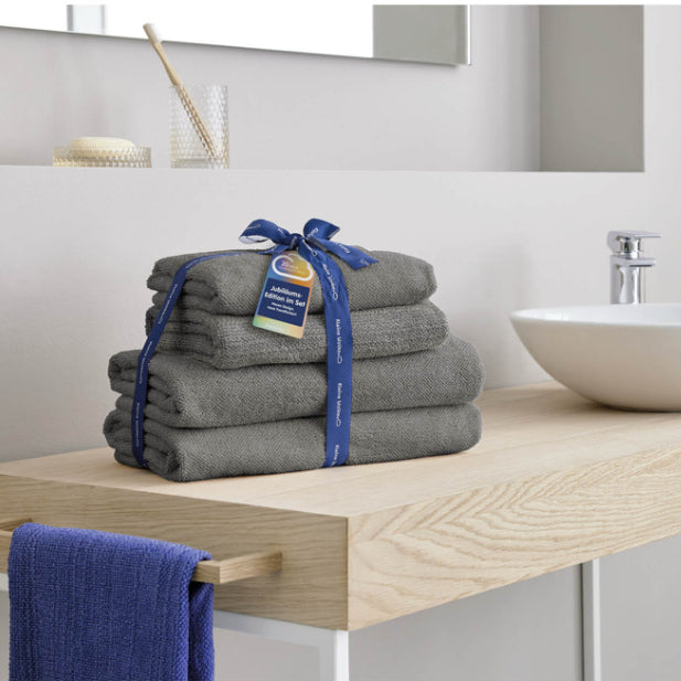 Graue Kleine-Wolke-Frottierserie Chill als Handtuch-Set auf Holzablage im modernen Badezimmer.