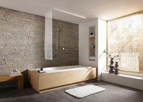 Moderne Badewanne aus Holz mit Duscharmatur vor Steinwand und Fenster