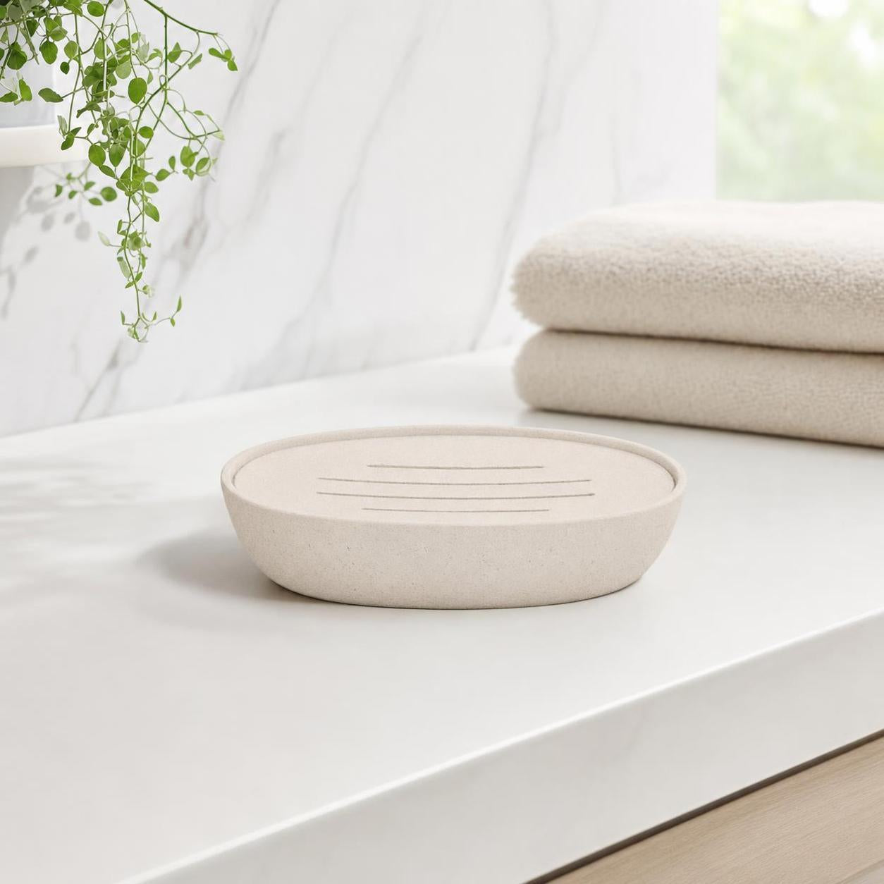 Beige Seifenschale aus Keramik auf weißem Waschbecken im Bad.
