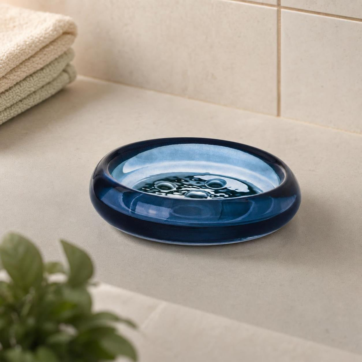 Blaue Seifenschale aus Glas steht auf einer hellen Badezimmerablage.