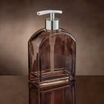 Transparenter brauner Seifenspender mit silberner Pumpe auf Tisch