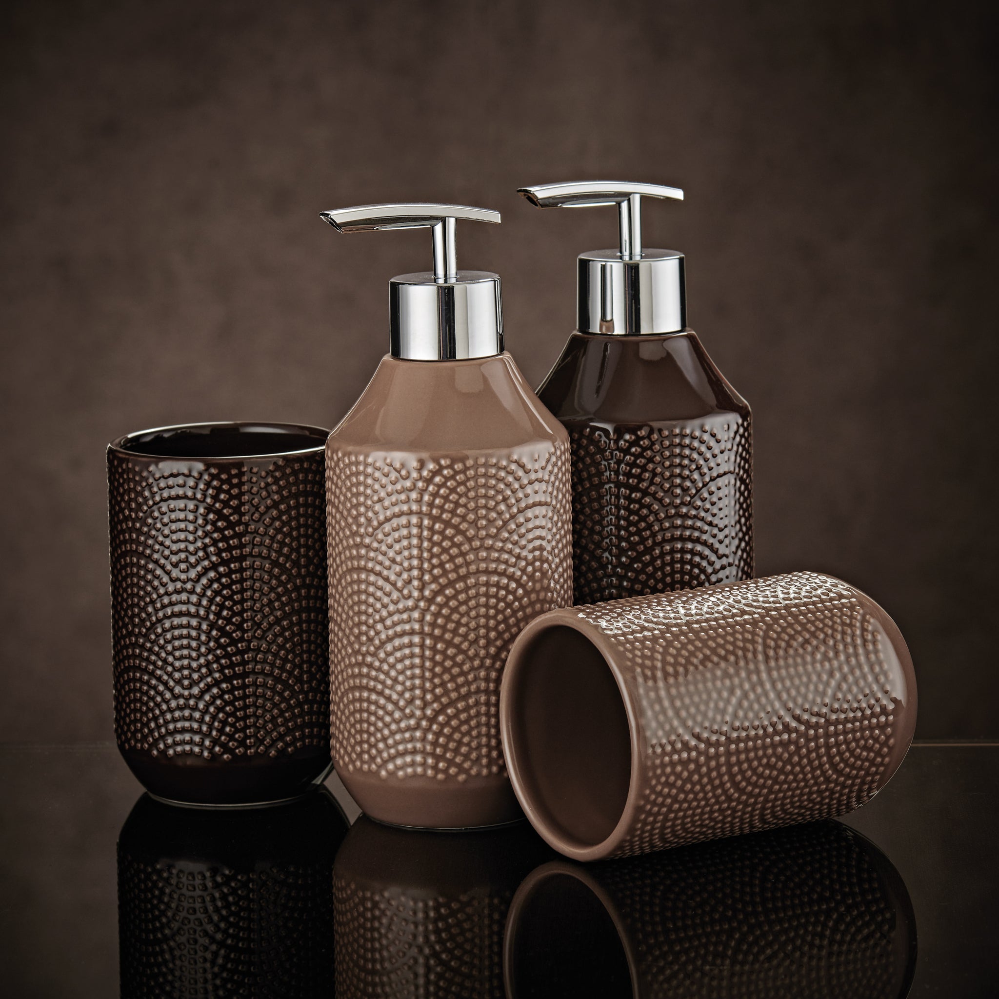 Seifenspender BOW Nussbraun mit passendem Becher-Set vor braunem Hintergrund arrangiert.