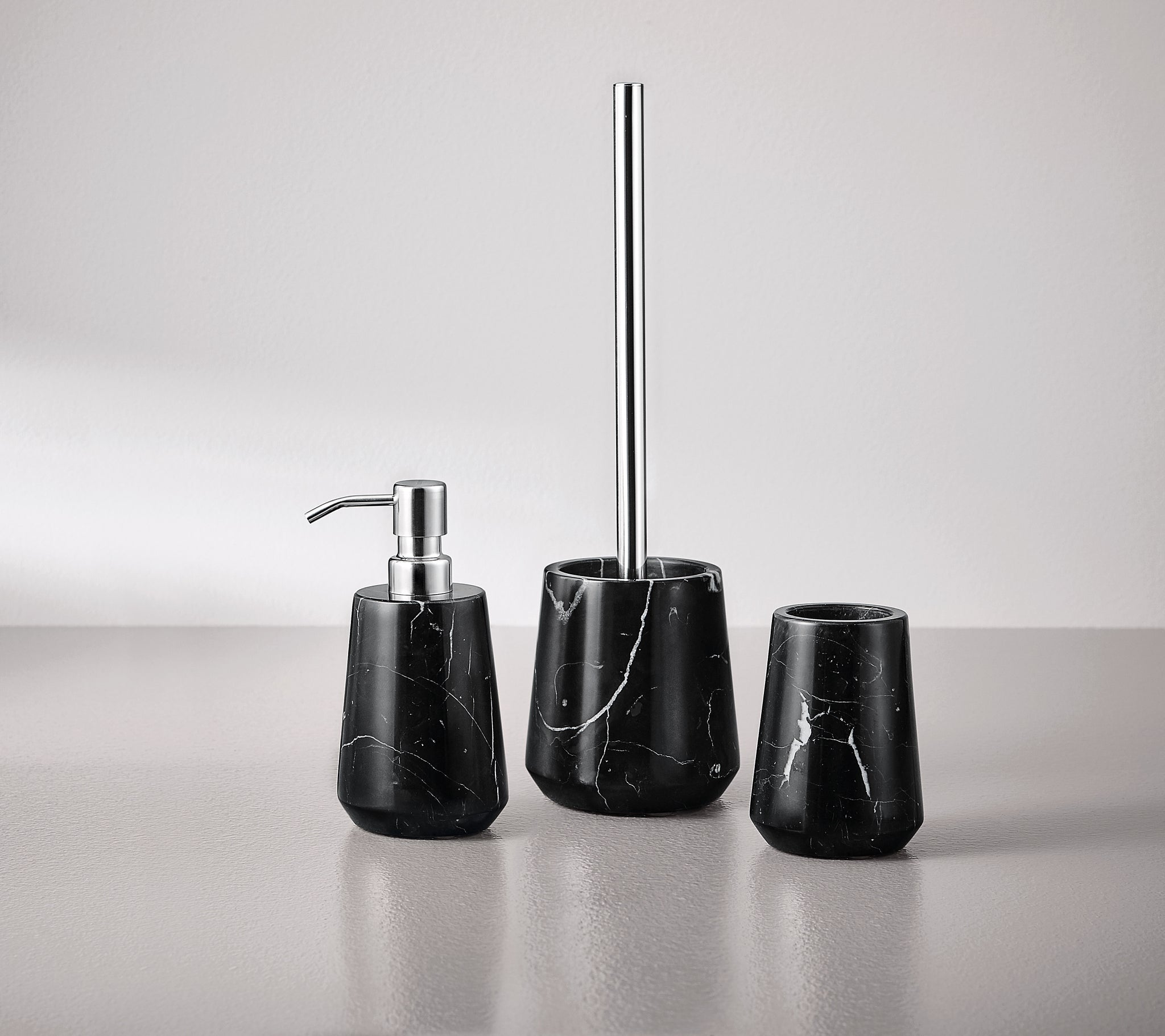 Seifenspender CARRARA Schwarz aus schwarzem Marmor steht mit passenden Badaccessoires auf einem Waschbecken.