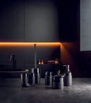 Schwarze Badaccessoires vor dunklem Waschbecken mit LED-Beleuchtung