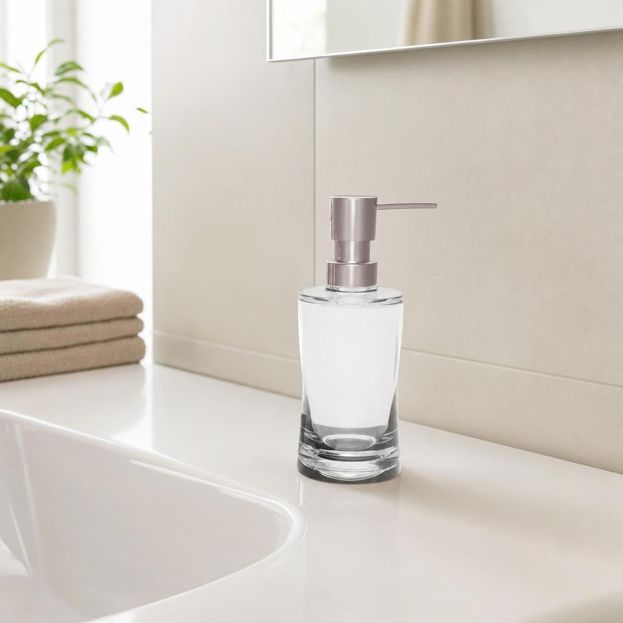 Ein Glas-Seifenspender steht auf einem weißen Waschbecken im Bad.