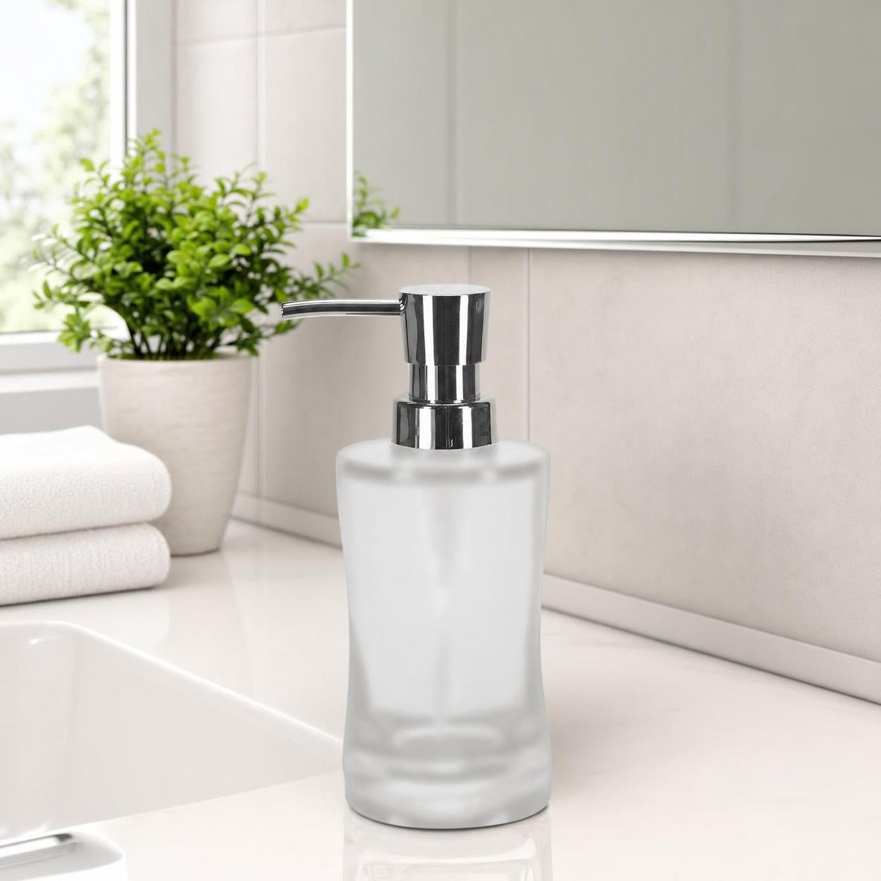 Ein matter Glas-Seifenspender mit Chrompumpe steht am Waschbecken.