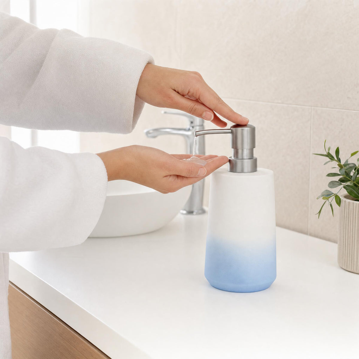 Hand drückt Seifenspender auf weißem Waschtisch im hellen Badezimmer.