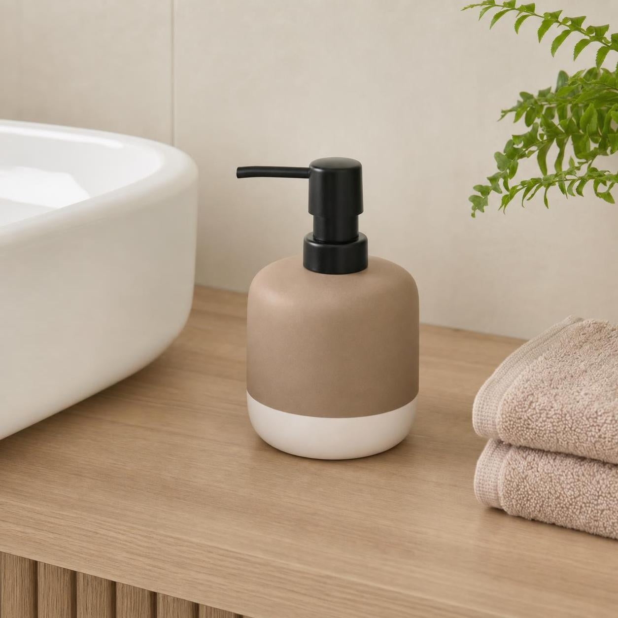 Ein beige-weißer Seifenspender mit schwarzer Pumpe steht am Waschbecken.