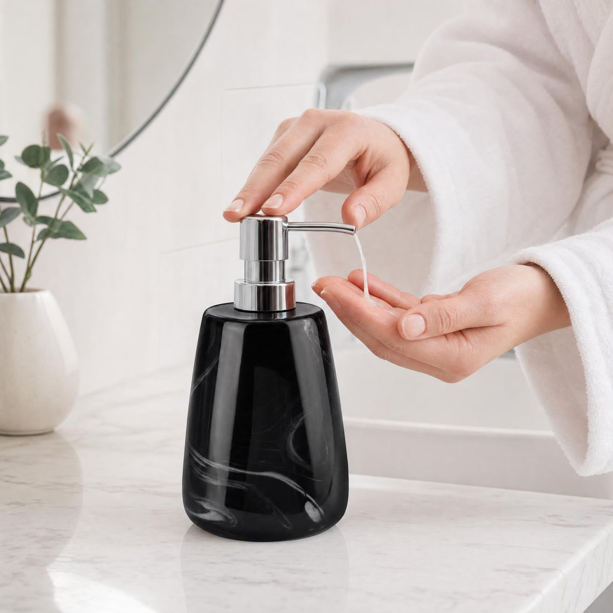 Hand pumpt Seife aus schwarzem Seifenspender auf Waschbeckenrand.