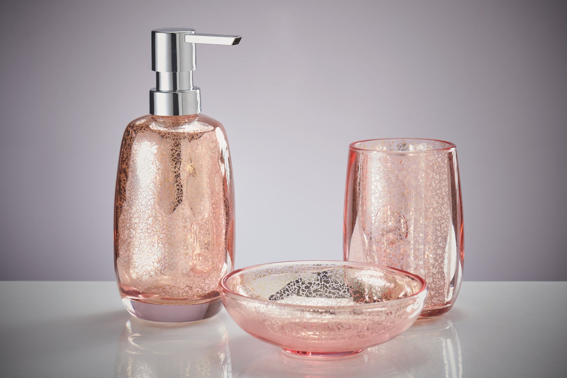 Seifenspender MERCURY Koralle mit passendem Becher und Schale auf weißer Fläche vor grauem Hintergrund.