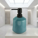 Türkiser Keramik-Seifenspender mit schwarzem Pumpkopf im Bad auf Ablage
