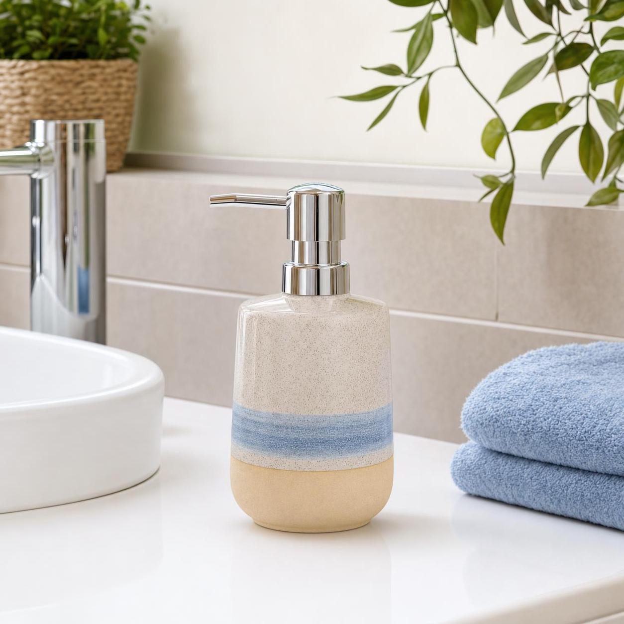 Beige-blauer Keramik-Seifenspender mit Chrompumpe steht am Waschbecken.