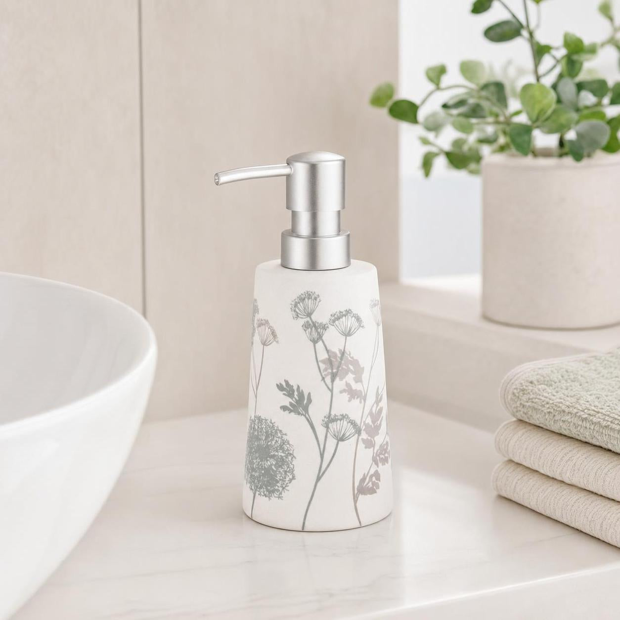 Ein weißer Seifenspender mit grauem Blumenmuster steht am Waschbecken.