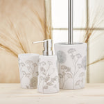 Weißes Badaccessoire-Set mit floralen Motiven auf Holzoberfläche