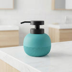 Türkiser Seifenspender mit schwarzem Pumpkopf auf weißer Arbeitsplatte