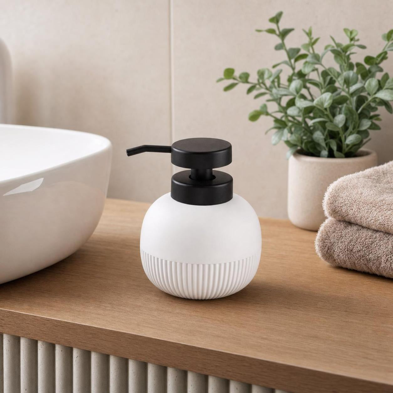 Ein weißer Seifenspender mit schwarzer Pumpe steht auf einem Holzwaschtisch.