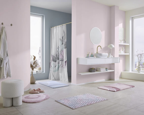 Modernes Bad in Rosa mit Waschtisch, Duschvorhang und Teppichen.