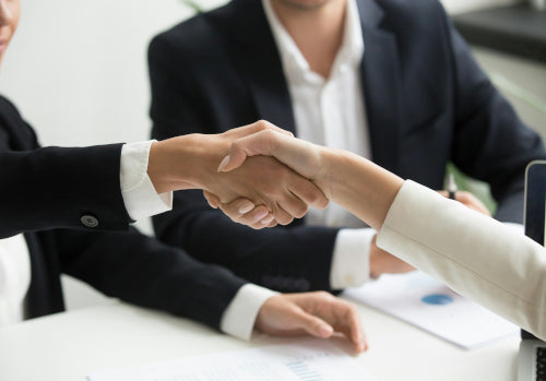 Zwei Geschäftsleute reichen sich im Büro beim Kleine Wolke Karriere Gespräch zur Vereinbarung die Hand.