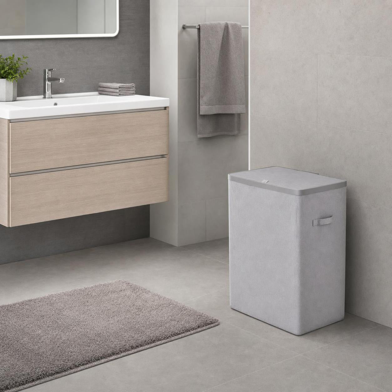 Ein grauer Wäschekorb steht in einem modernen Badezimmer.