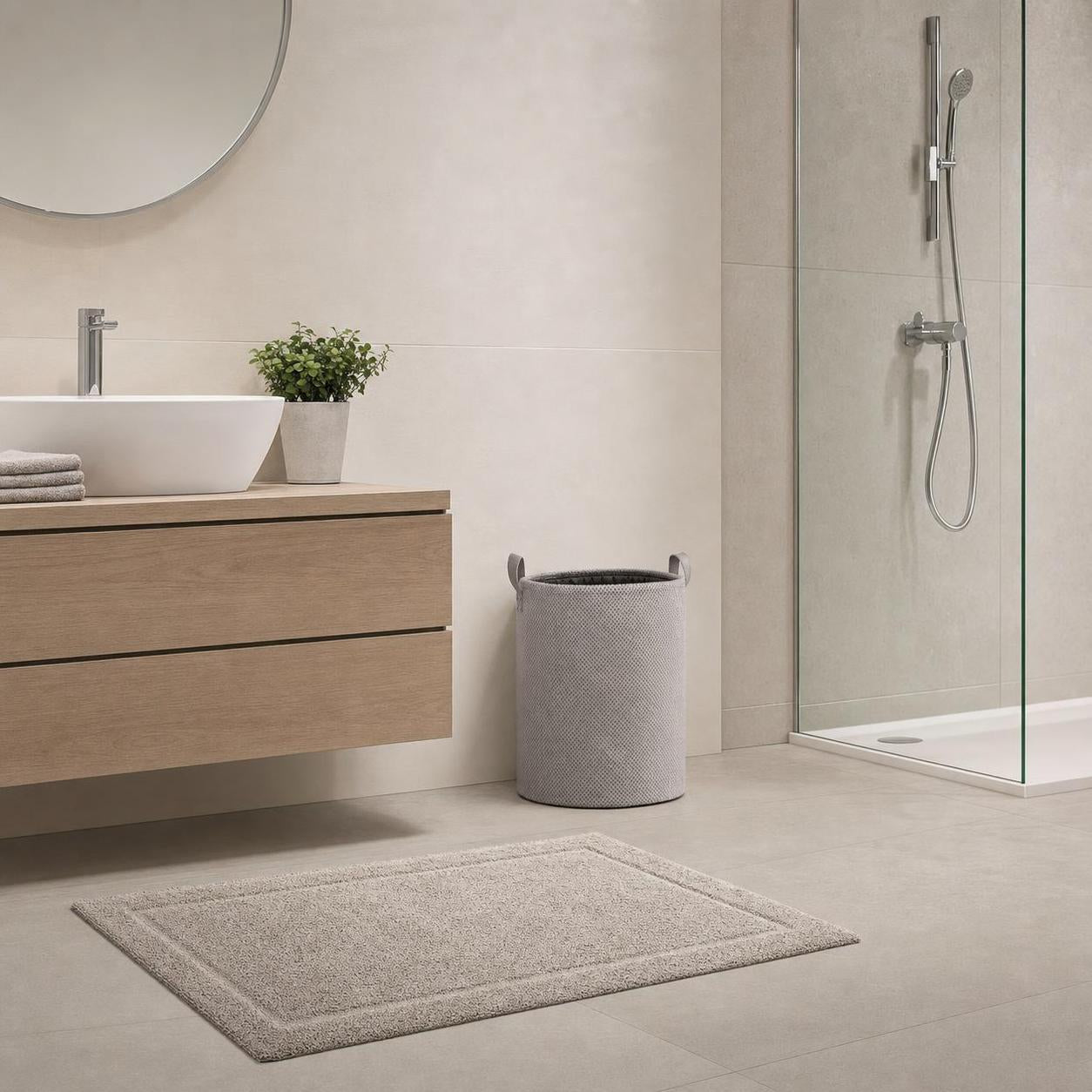 Beige Badematte liegt vor Waschtisch und Dusche im modernen Bad.